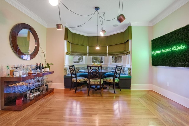 dining area featuring ornamental molding, bar area, and hardwood / wood-style flooring