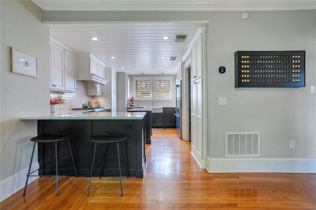 kitchen with kitchen peninsula, light hardwood / wood-style flooring, a breakfast bar, white cabinets, and high end fridge