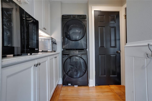 laundry room featuring stacked washer and clothes dryer and light wood-type flooring