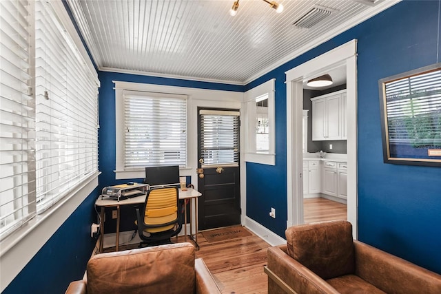 home office with crown molding and light hardwood / wood-style flooring