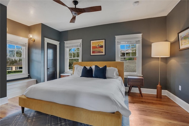 bedroom featuring ceiling fan, wood-type flooring, and multiple windows