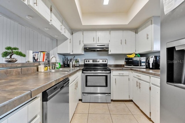 kitchen featuring stainless steel counters, white cabinetry, appliances with stainless steel finishes, and a tray ceiling