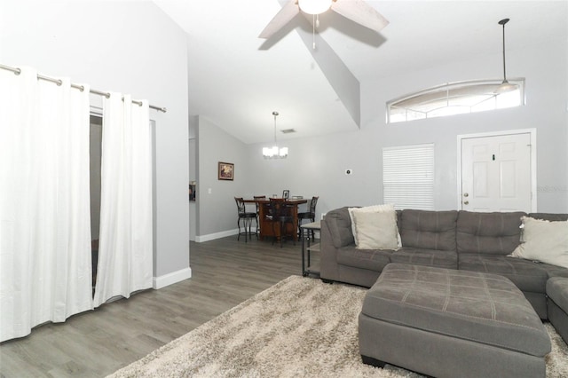 living room featuring wood-type flooring, ceiling fan with notable chandelier, and high vaulted ceiling