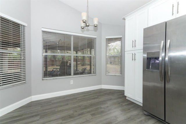 unfurnished dining area with lofted ceiling, dark wood-type flooring, and an inviting chandelier