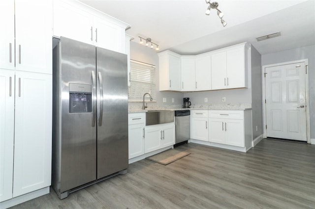 kitchen with light stone counters, stainless steel appliances, sink, light hardwood / wood-style floors, and white cabinetry