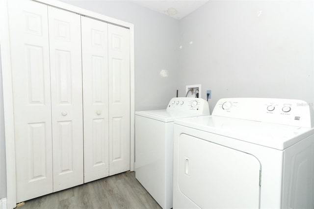 clothes washing area featuring separate washer and dryer and light hardwood / wood-style floors