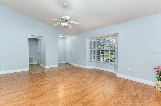 empty room with light wood-type flooring, visible vents, vaulted ceiling, and baseboards