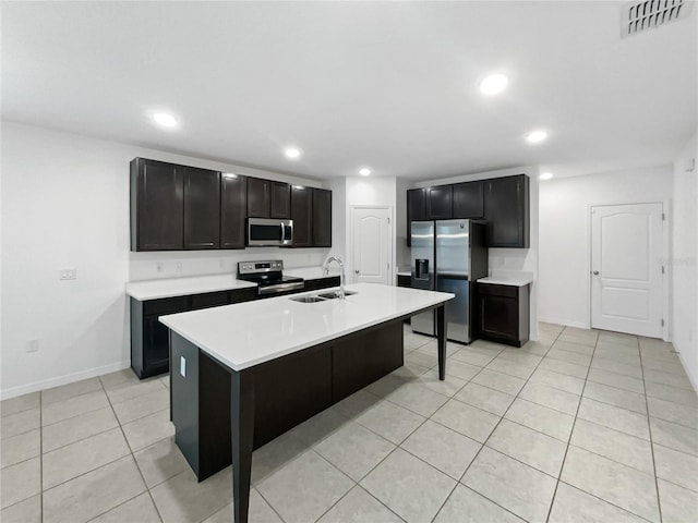 kitchen featuring a center island with sink, sink, appliances with stainless steel finishes, light tile patterned flooring, and a breakfast bar area