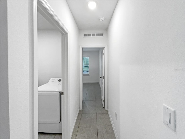 hallway with light tile patterned floors and washer / dryer