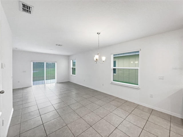 spare room with light tile patterned flooring and an inviting chandelier