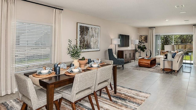 tiled dining space with a textured ceiling and a wealth of natural light