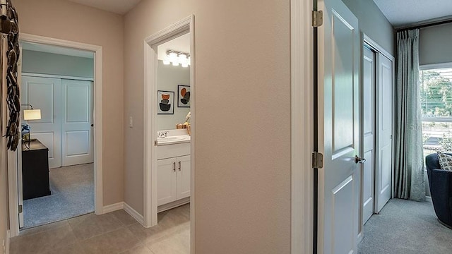 hall featuring sink and light colored carpet