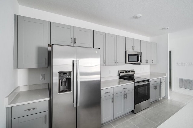 kitchen featuring appliances with stainless steel finishes, gray cabinetry, and light tile patterned floors