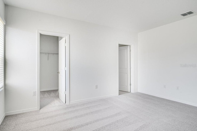 unfurnished bedroom featuring light carpet and a spacious closet