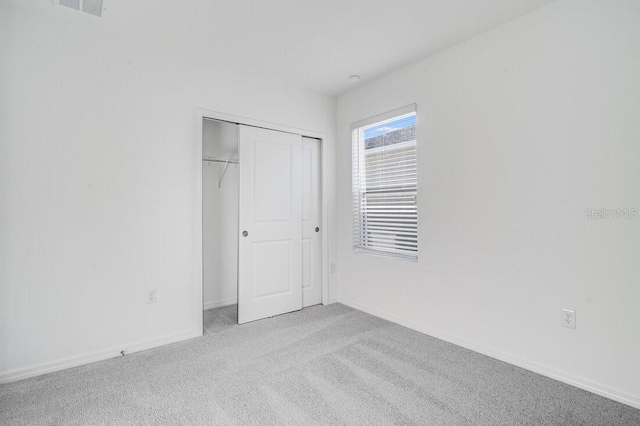 unfurnished bedroom featuring light carpet and a closet