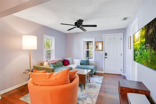 living room featuring dark hardwood / wood-style floors, ceiling fan, and a textured ceiling