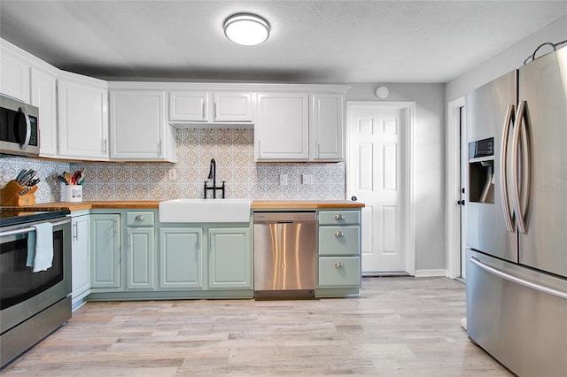 kitchen featuring butcher block countertops, sink, white cabinets, and appliances with stainless steel finishes