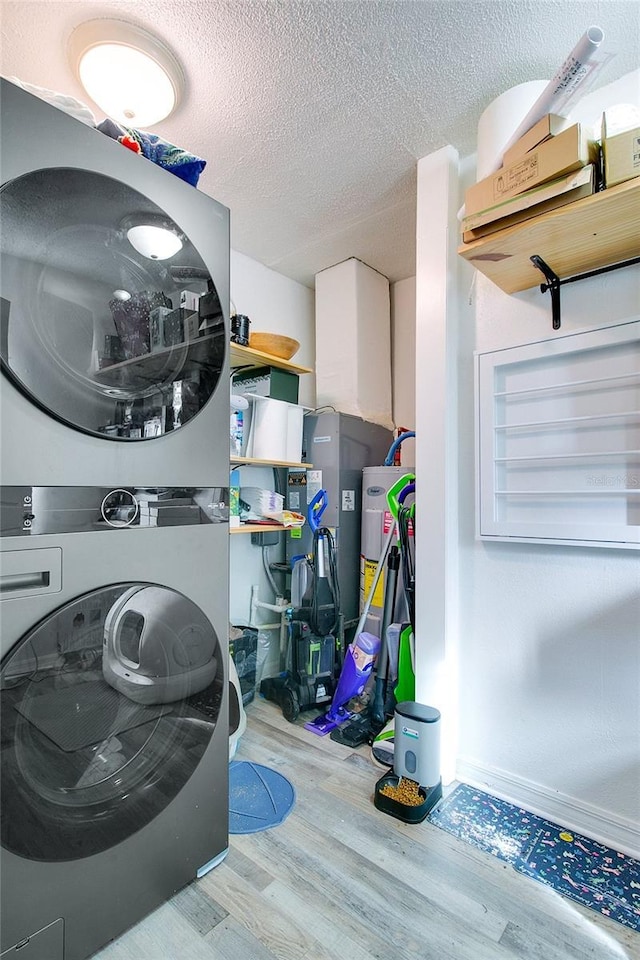 washroom featuring a textured ceiling, light wood-type flooring, and stacked washing maching and dryer