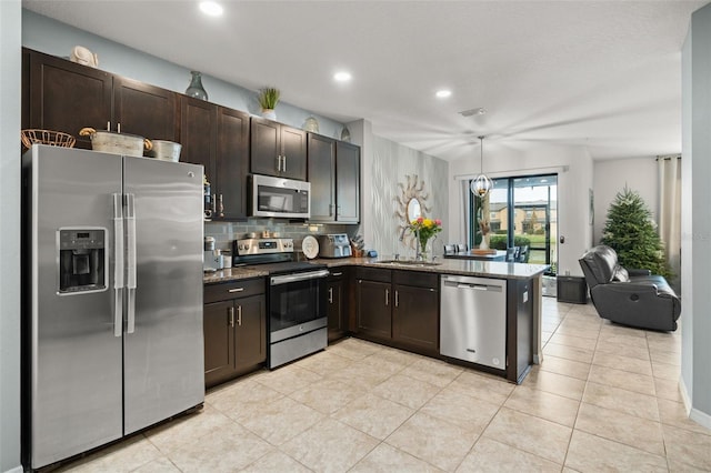 kitchen with tasteful backsplash, kitchen peninsula, dark brown cabinets, light tile patterned floors, and appliances with stainless steel finishes