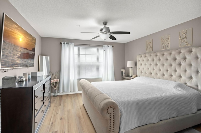 bedroom with ceiling fan, light hardwood / wood-style floors, and a textured ceiling