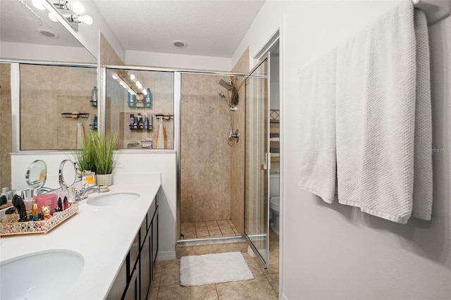 bathroom featuring tile patterned flooring, vanity, toilet, and a shower with shower door