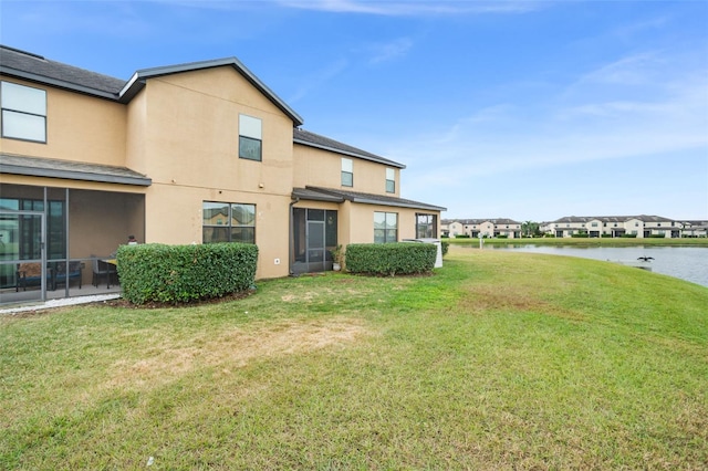 rear view of house featuring a yard and a water view