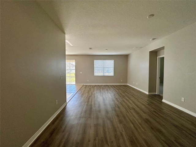 empty room with a textured ceiling and dark hardwood / wood-style flooring