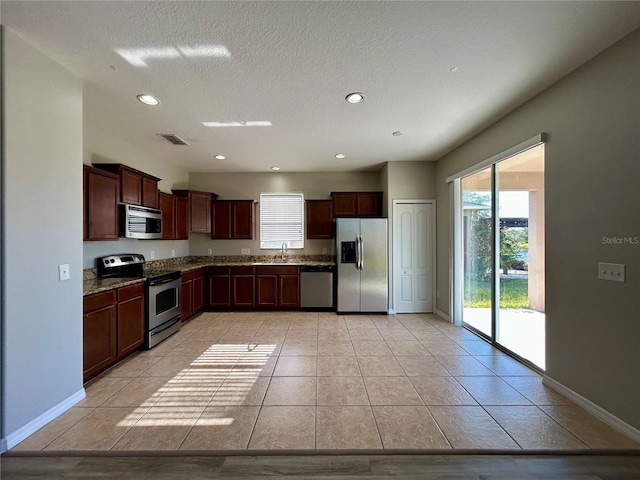 kitchen featuring light stone counters, sink, light tile patterned flooring, and appliances with stainless steel finishes