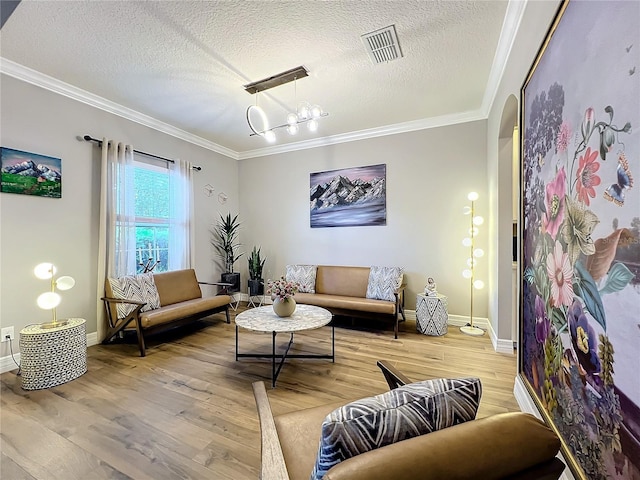 living room featuring a chandelier, wood-type flooring, a textured ceiling, and crown molding