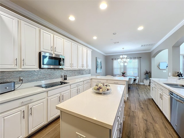 kitchen with kitchen peninsula, sink, appliances with stainless steel finishes, decorative light fixtures, and white cabinetry