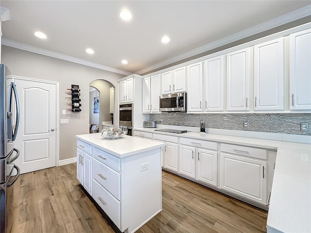 kitchen featuring white cabinets, crown molding, light hardwood / wood-style floors, a kitchen island, and stainless steel appliances