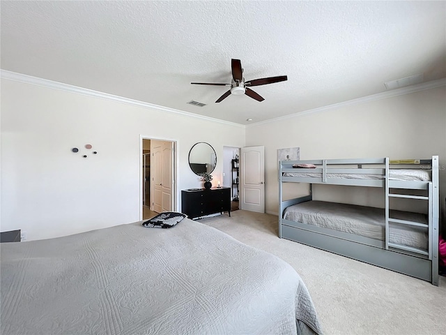 carpeted bedroom with ceiling fan, a textured ceiling, and ornamental molding