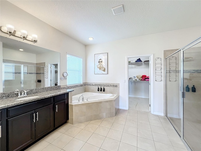 bathroom with tile patterned flooring, vanity, a textured ceiling, and independent shower and bath