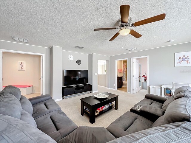 living room featuring light carpet, ceiling fan, and a textured ceiling