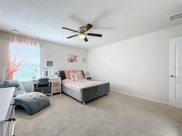 bedroom with ceiling fan, light colored carpet, and a textured ceiling