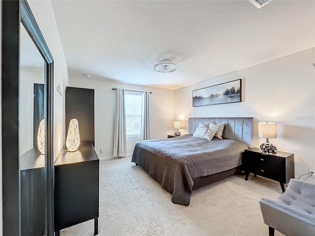 bedroom with a textured ceiling and light colored carpet