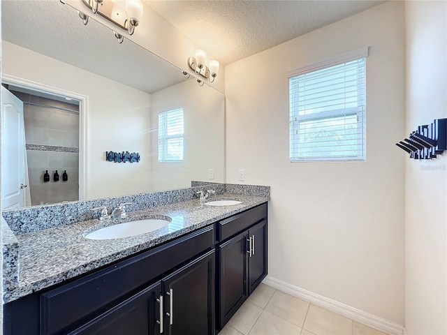 bathroom with a wealth of natural light, tile patterned flooring, vanity, and a textured ceiling