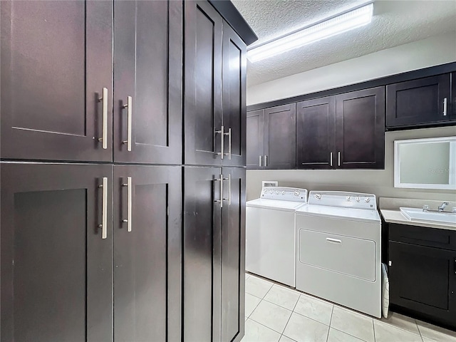 laundry area with sink, cabinets, a textured ceiling, light tile patterned floors, and washer and dryer