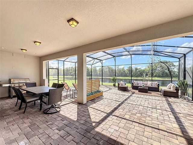 view of patio / terrace with glass enclosure, a grill, an outdoor kitchen, and an outdoor hangout area