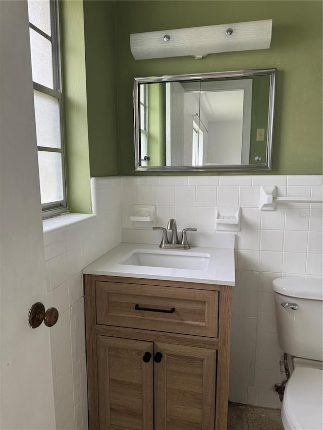 bathroom with vanity, toilet, and tile walls