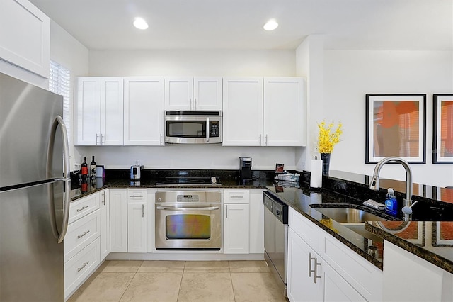 kitchen with white cabinets, appliances with stainless steel finishes, dark stone counters, and sink