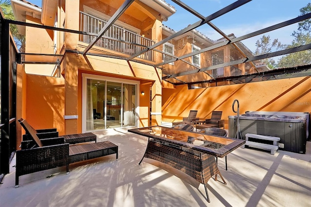 view of patio with glass enclosure, a balcony, and a hot tub