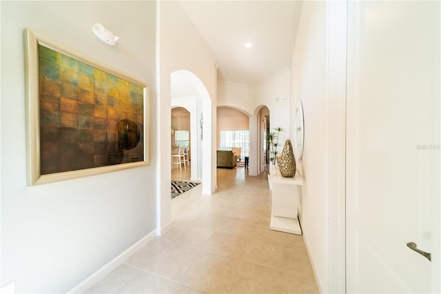 hallway with light tile patterned floors and crown molding