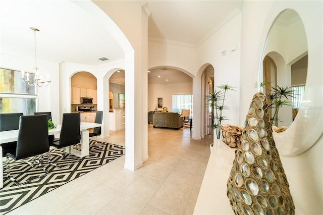 tiled foyer featuring crown molding and a notable chandelier