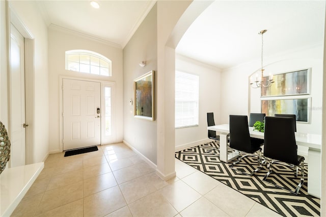 tiled entrance foyer featuring crown molding, a wealth of natural light, and a chandelier