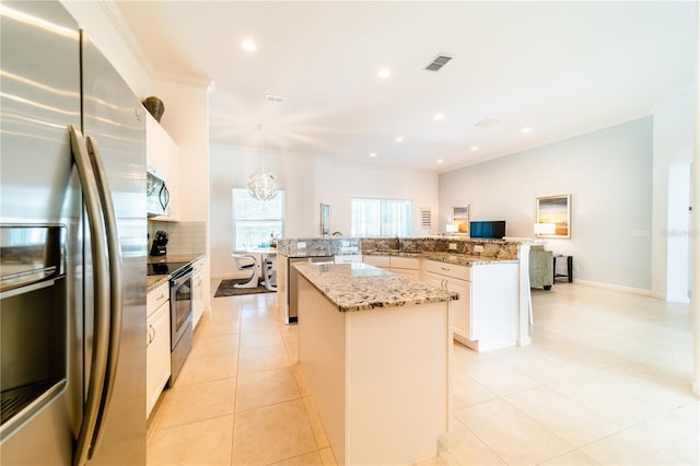 kitchen with stainless steel appliances, a kitchen island, light tile patterned floors, white cabinetry, and hanging light fixtures