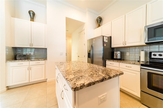 kitchen with white cabinets, light tile patterned floors, stainless steel appliances, and a kitchen island