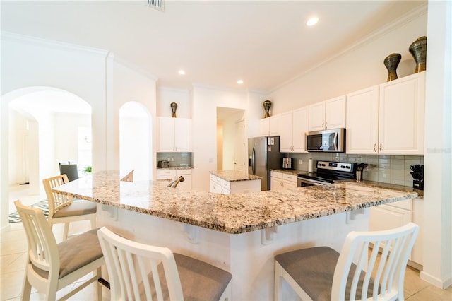 kitchen with a kitchen bar, light stone countertops, a spacious island, and appliances with stainless steel finishes