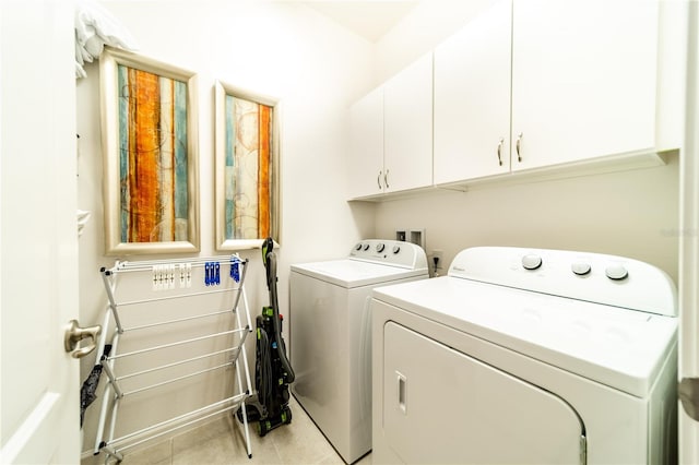 laundry room featuring cabinets, light tile patterned floors, and washing machine and dryer