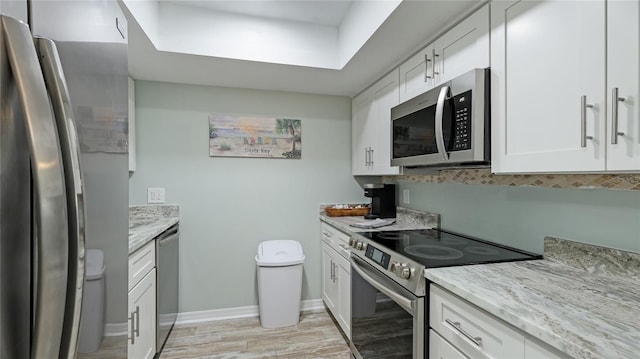 kitchen featuring light stone countertops, light hardwood / wood-style flooring, white cabinets, and stainless steel appliances